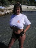 Shameless older babe soaks her white tee up to flash her big jugs at the beach
