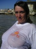 Shameless older babe soaks her white tee up to flash her big jugs at the beach
