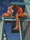 Two amazing cougars dressed as lifeguards flash their tits at a public beach