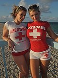 Two amazing cougars dressed as lifeguards flash their tits at a public beach