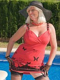 Sassy blonde milf posing by the pool in red high heels and a laced corset that flaunts her hot body